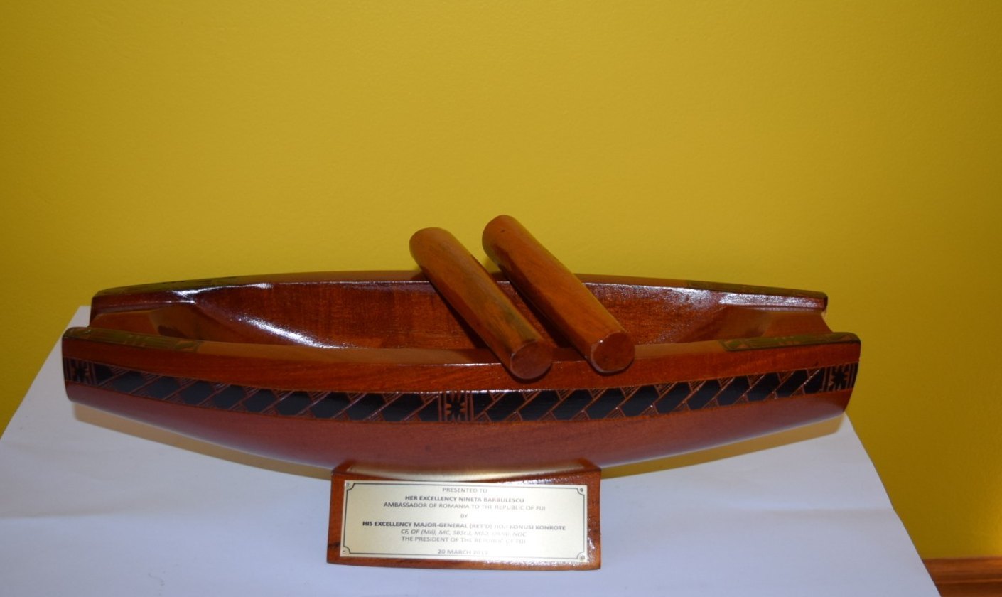 A Fijian lali drum carved in the form of a drua, with two beaters and a presentation plaque