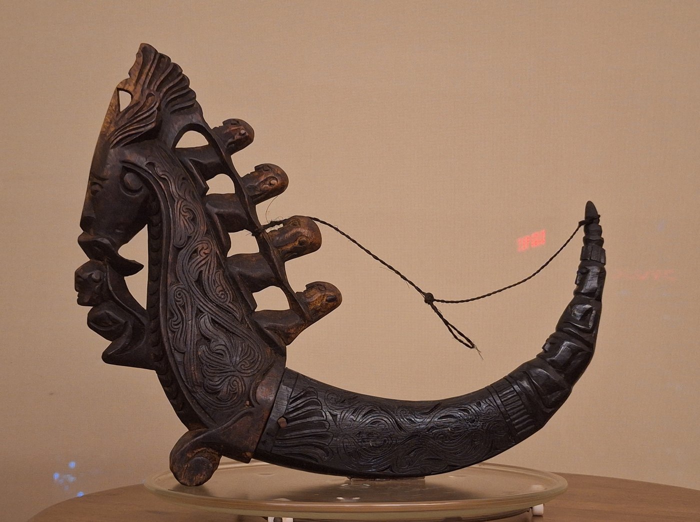 Plate 4 — a large, richly carved buffalo-horn naga morsarang with an openwork crest of a singa head and four seated figures